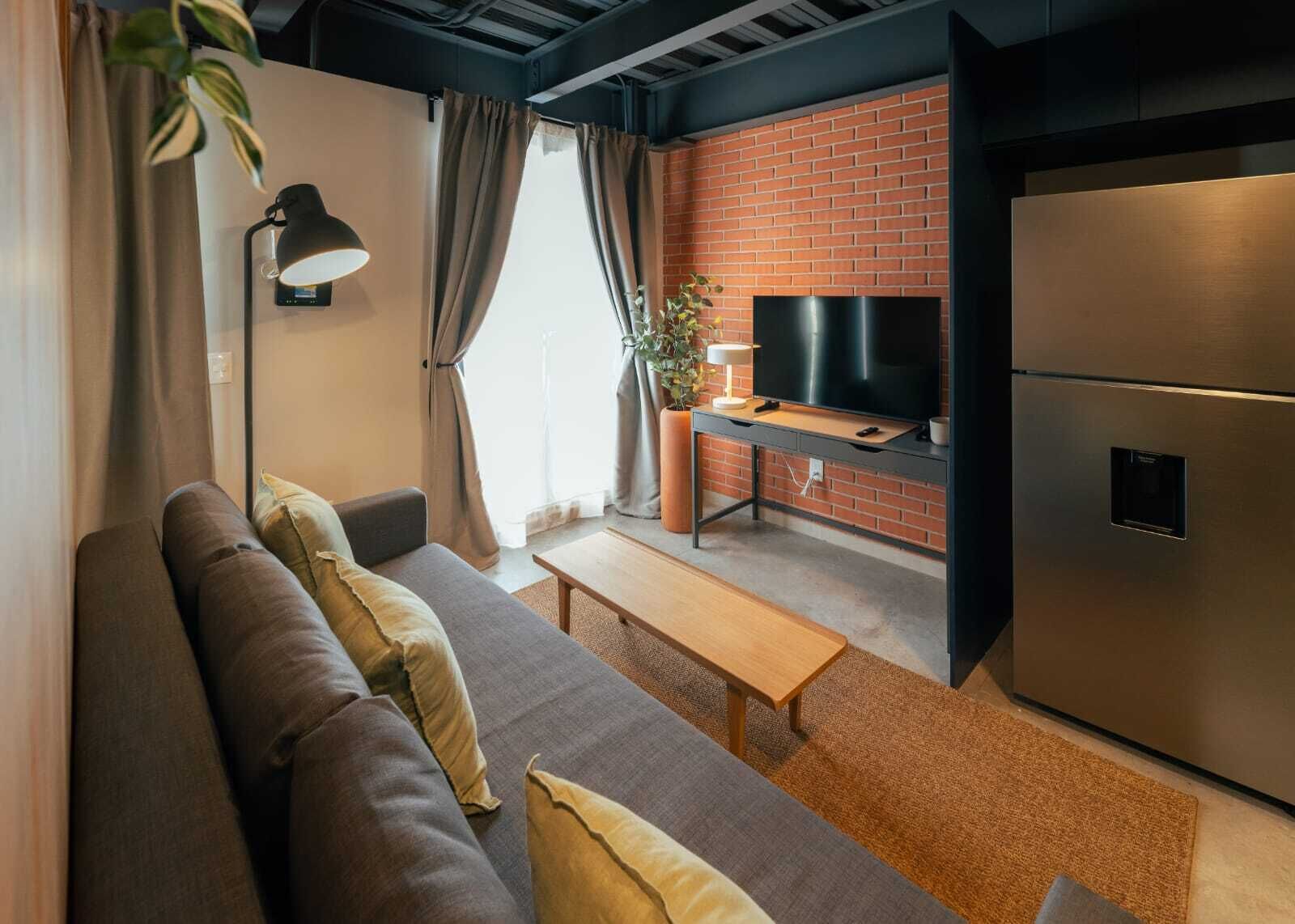 A modern living room with a sofa, a coffee table, a TV, and a refrigerator.
