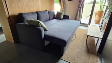 A room with a sofa, a small table, and a view through a glass door.