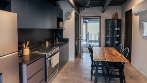 Cozinha moderna com armários escuros, uma mesa de jantar de madeira e vista para uma varanda.