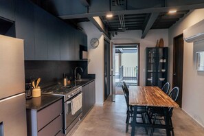 Eine moderne Küche mit dunklen Schränken, einem Holztisch und Blick auf einen Balkon.