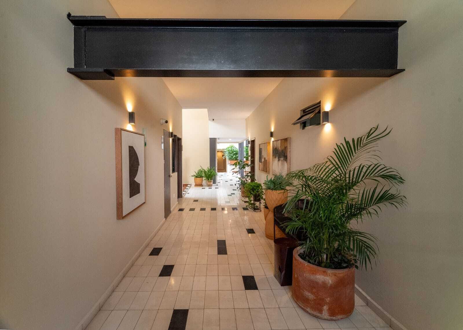 Un pasillo con piso de baldosas, luces empotradas en la pared y plantas en macetas.