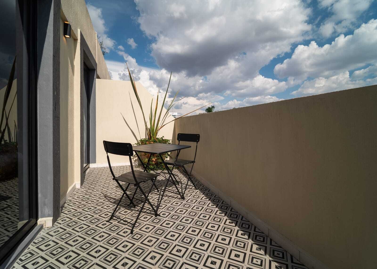 A patio with a patterned floor, a table, and two chairs.
