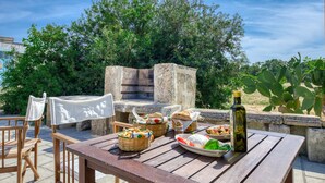 Un espace extérieur aménagé pour les repas, avec des tables et des chaises en pierre, ainsi que des paniers remplis de nourriture.