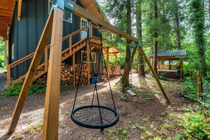 Eine Holzjagdhaus mit Schaukel und einem kleinen Holzgebäude im Wald.
