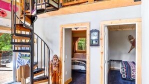 A wooden interior with a spiral staircase, two bedrooms, a dining area, and a view of the outdoors.
