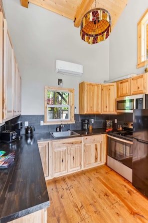 A kitchen with wooden cabinets, a black countertop, a stove, and a microwave.