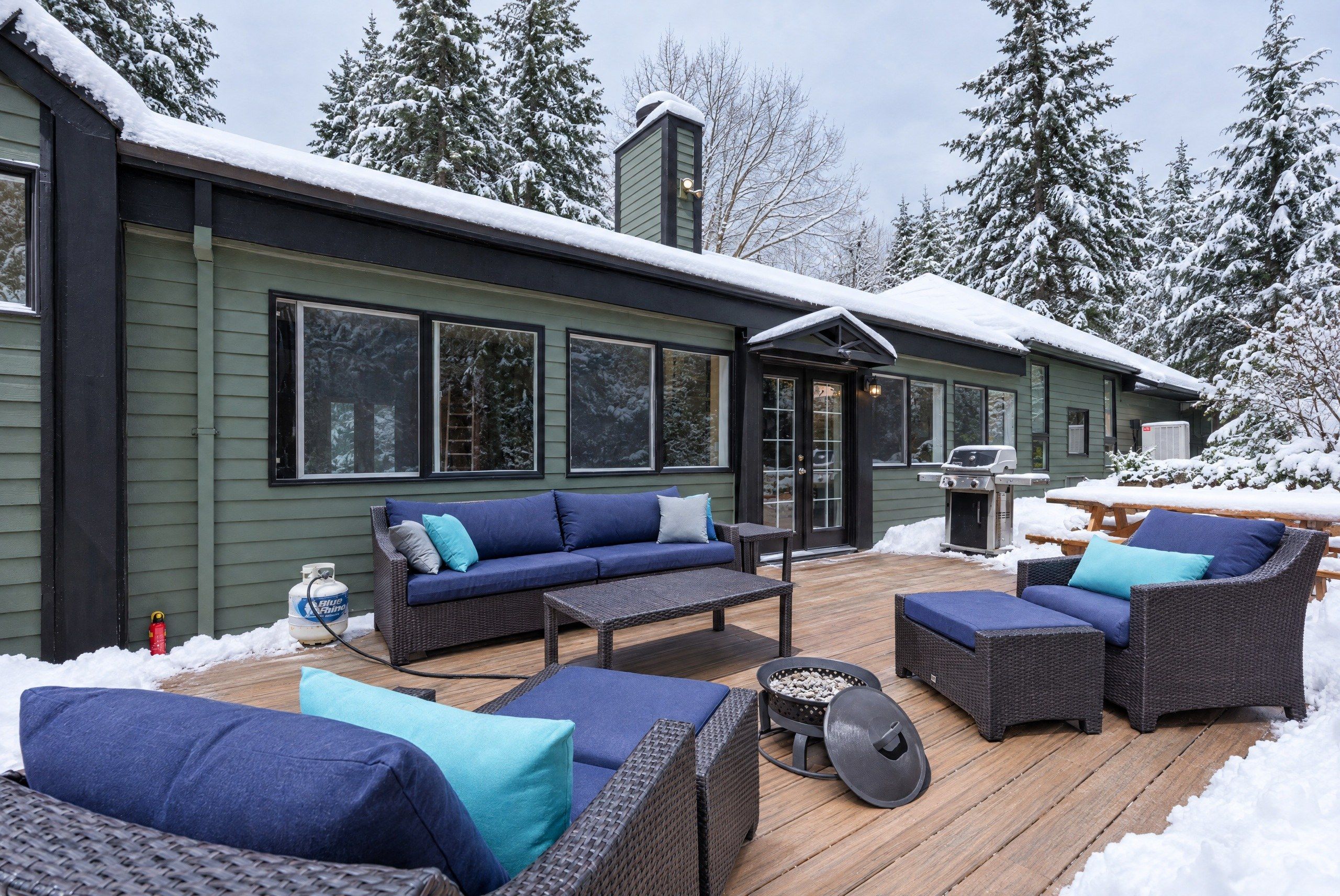 A covered outdoor deck with wicker furniture, a grill, and a propane tank.