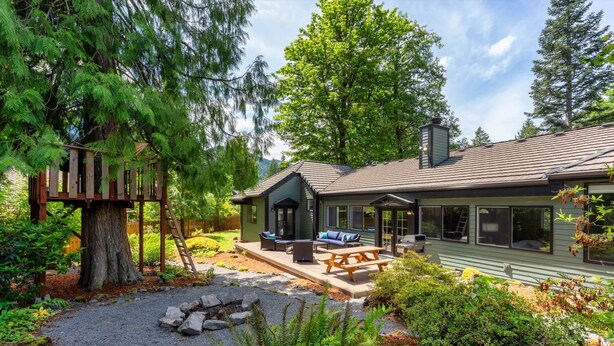 Ein Haus mit Terrasse, Sitzgelegenheiten im Freien und einem Kamin aus Stein.