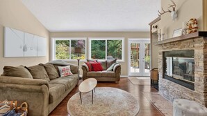 Ein Wohnzimmer mit Kamin, zwei Sofas, einem Couchtisch und einem großen Fenster.