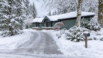 A snow-covered house with a driveway leading to the entrance.