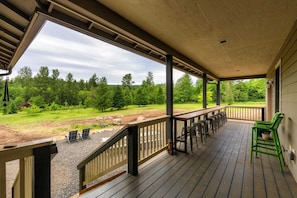 Une terrasse couverte avec des sièges d’extérieur, une vue sur une forêt et un espace recouvert de gravier.