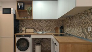 A compact kitchen with a washing machine, microwave, and a sink. - Casa Azahar Apartment Valencia (Valencia)
