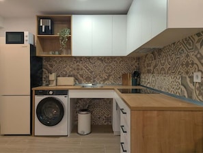 Una cucina compatta con lavatrice, forno a microonde e lavandino.