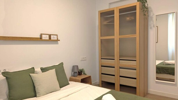 A bedroom with a bed, pillows, a nightstand, a wooden wardrobe, and a window. - Casa Azahar Apartment Valencia (Valencia)