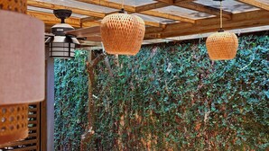 A covered outdoor area with a wooden ceiling, hanging woven light fixtures, and a wall covered in ivy. - Luxury Cozy Home in San Nicolas (San Miguel)