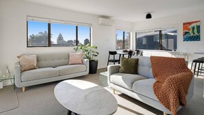 Un salon moderne comprenant deux canapés, une table basse et un coin repas avec des chaises et une table.