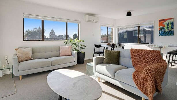 A modern living room with two sofas, a coffee table, and a dining area with chairs and a table.