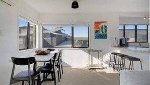 Une cuisine moderne avec un coin repas, de grandes fenêtres et une vue sur le quartier.
