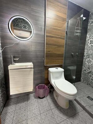 Une salle de bain avec des toilettes, un lavabo et une douche.