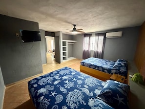 A room with two beds, a ceiling fan, an air conditioning unit, a TV, and a view of a corridor. - Villa Cielo y Mar Playa Miramar (Ciudad Madero)