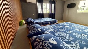 A room with two beds, a ceiling fan, an air conditioning unit, a window with curtains, and a small plant.