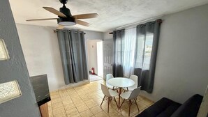 A room with a ceiling fan, a dining table with chairs, a sofa, and a tiled floor.