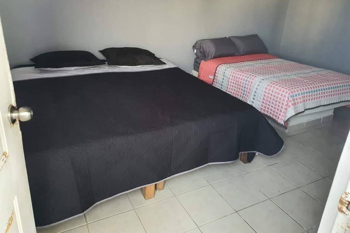 A bedroom with two beds, one with a black bedspread and the other with a patterned bedspread.