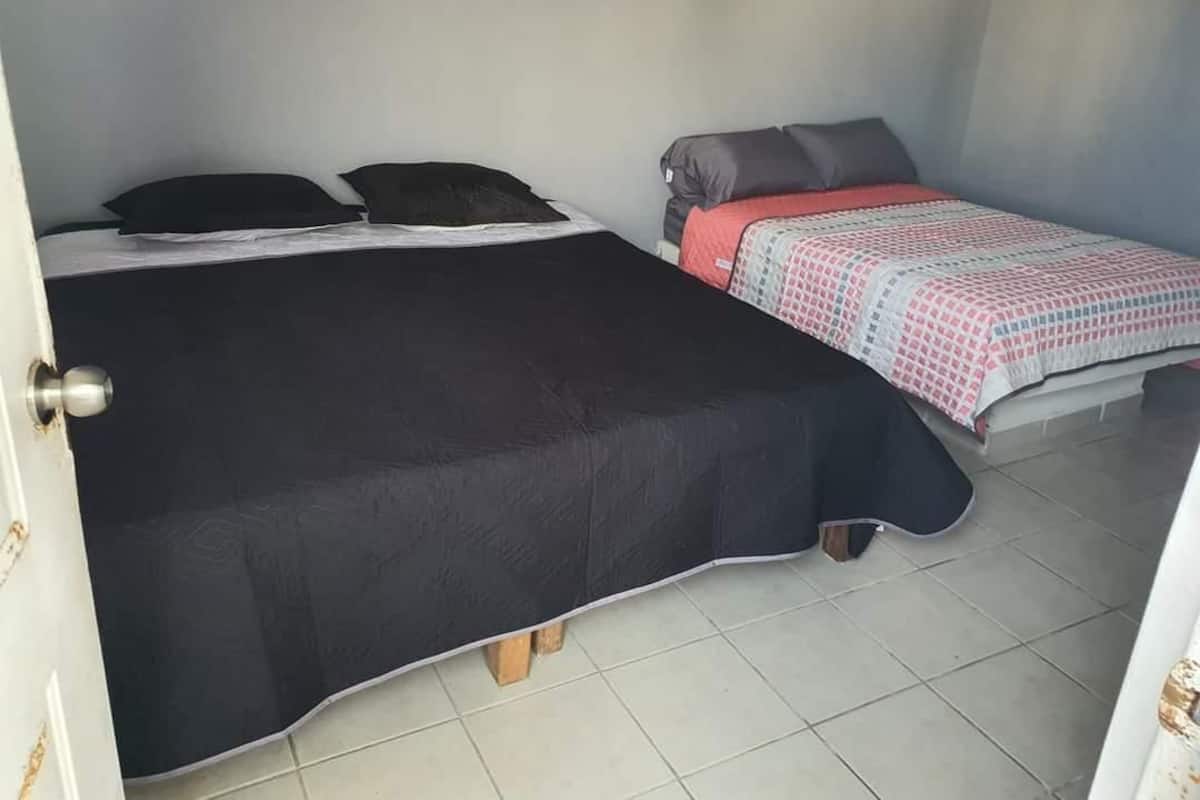 Une chambre avec deux lits, l’un recouvert d’une couvre-lit noire et l’autre d’une couvre-lit à motifs.