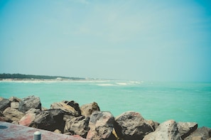A coastal view with large rocks in the foreground and a clear sky.