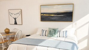 A bedroom with a bed, a dining table, chairs, and artwork on the walls. - 30A Studio - Seaside/Pool/Beach Walking Distance (Santa Rosa Beach)