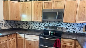 A kitchen with wooden cabinets, a granite countertop, a stainless steel oven, and a microwave.