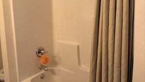 A bathtub with a shower curtain, a handheld showerhead, and a towel rack with a towel.