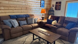 A cozy living room with a brown leather sofa, a wooden coffee table, and a patterned rug.