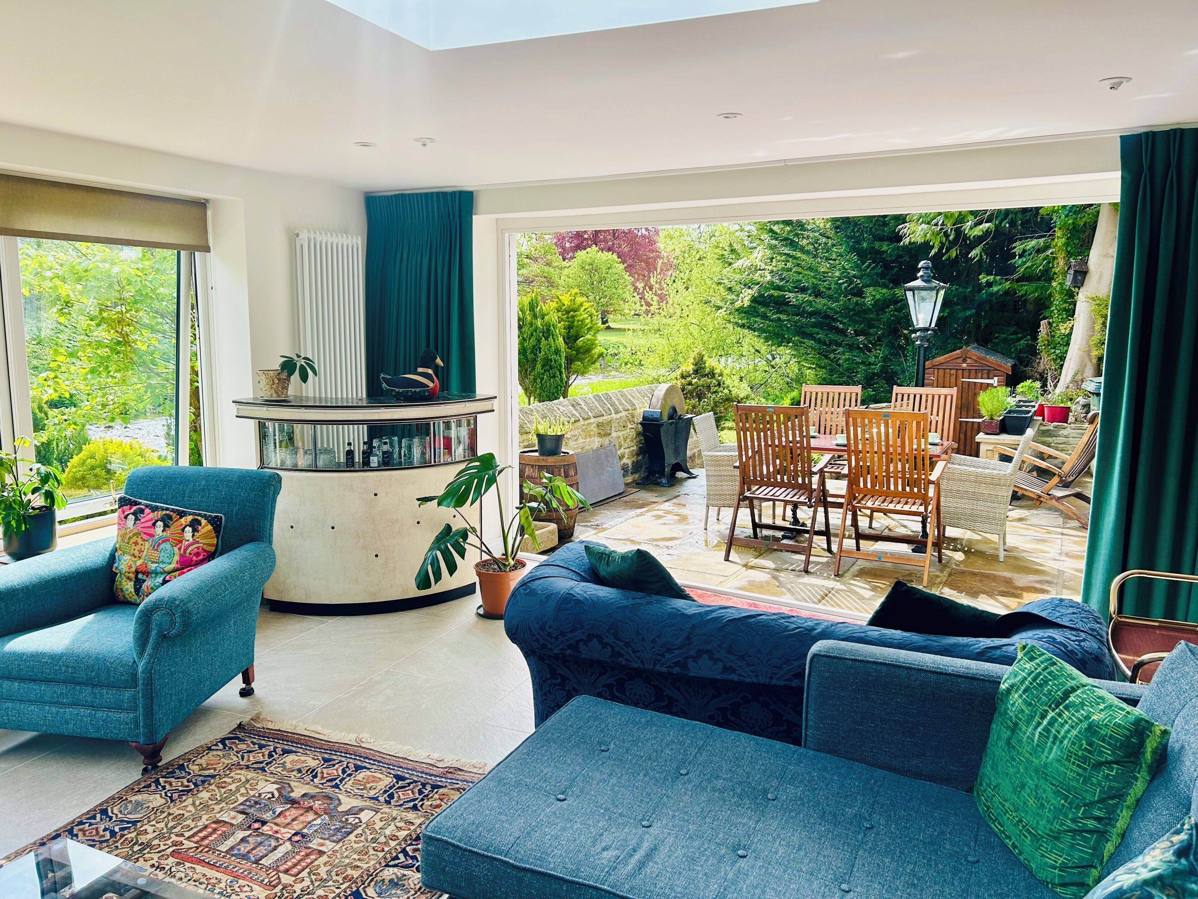A living room with a sofa, armchair, and a coffee table. There is a view of an outdoor patio with chairs and a table.