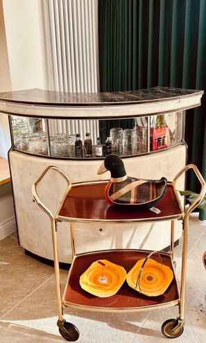 Eine Bar mit einem runden Tisch, einer Entenfigur und einem Wagen mit orangefarbenen Tellern.