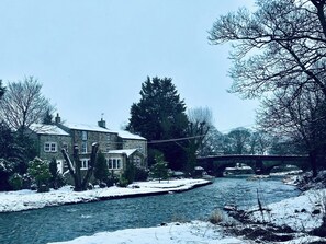 Ein Steinhaus mit vielen Fenstern und einem mit Schnee bedeckten Fluss.