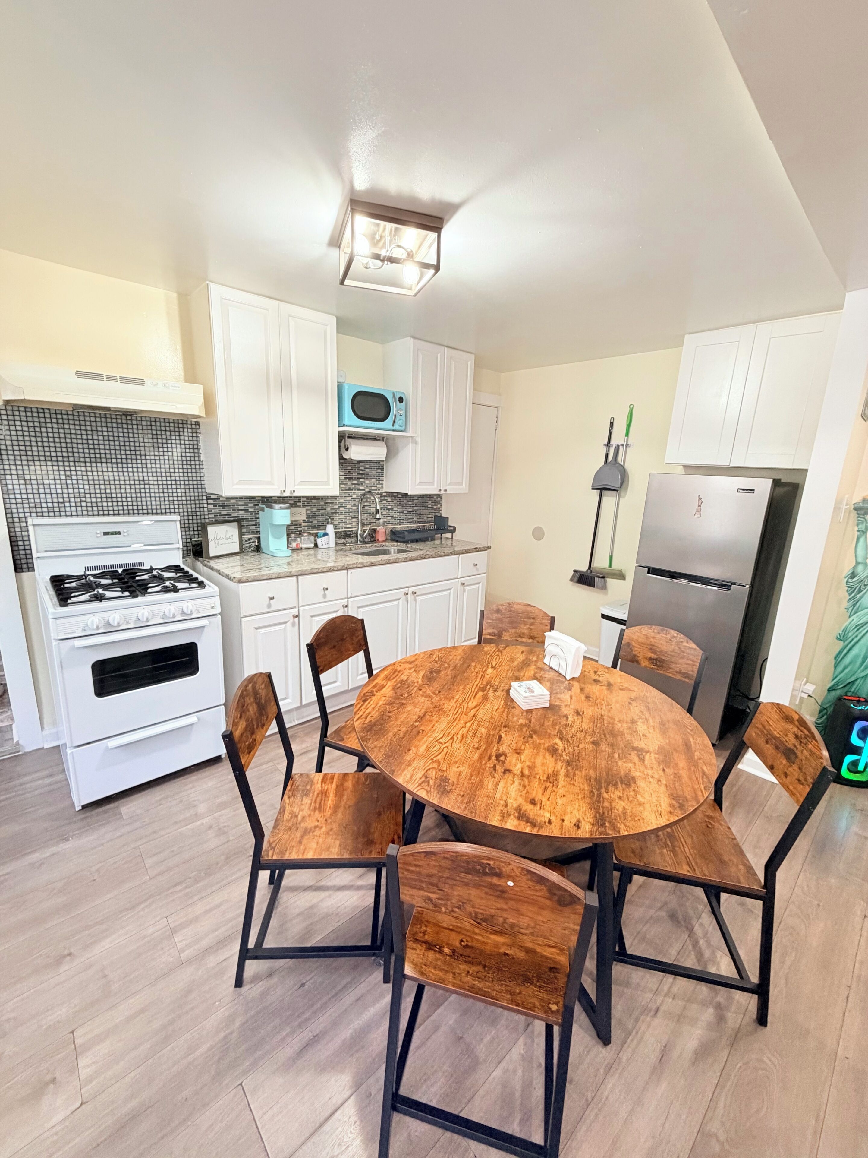 A modern kitchen with white cabinets, a wooden dining table, and a built-in microwave.