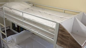 A bunk bed with drawers and a shelf, a wooden floor, and a wall with a comic book style sticker.