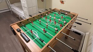 A foosball table in a room with a bunk bed and a wardrobe.