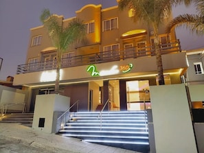 A hotel with a modern design, featuring a prominent entrance with illuminated steps and a balcony.