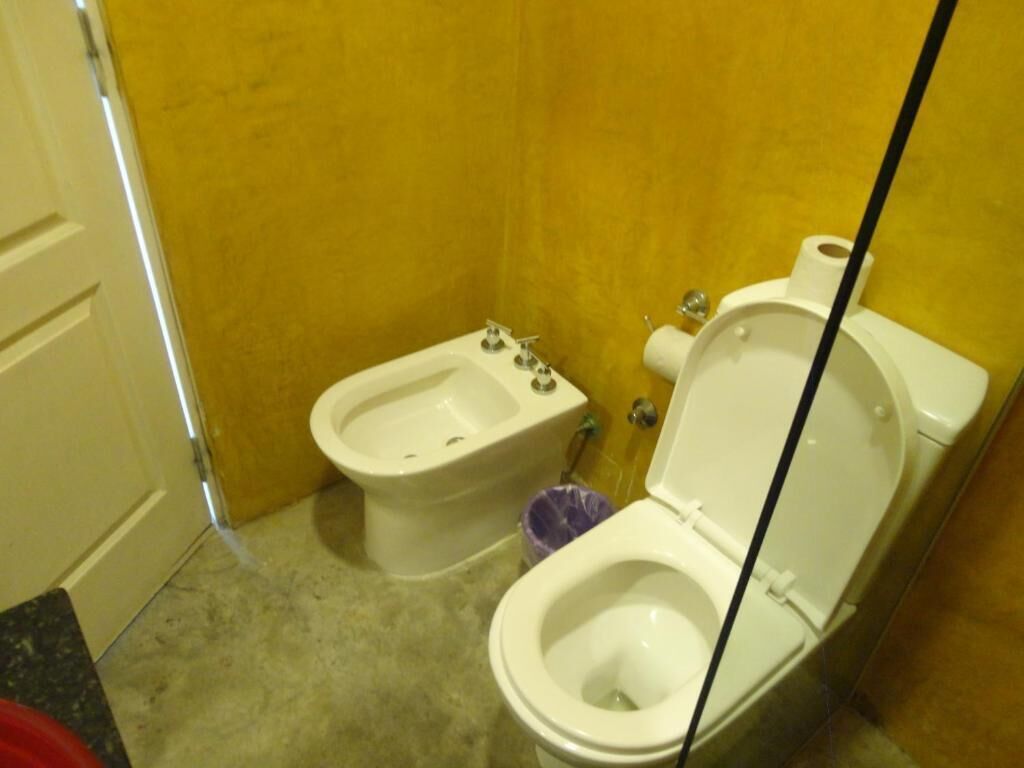 Un baño con bidé, inodoro y cubo de basura.