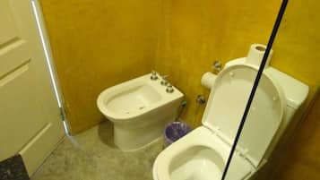 Un baño con bidé, inodoro y cubo de basura.