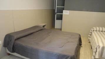 Un dormitorio con cama, mesita de noche, armario y una puerta.