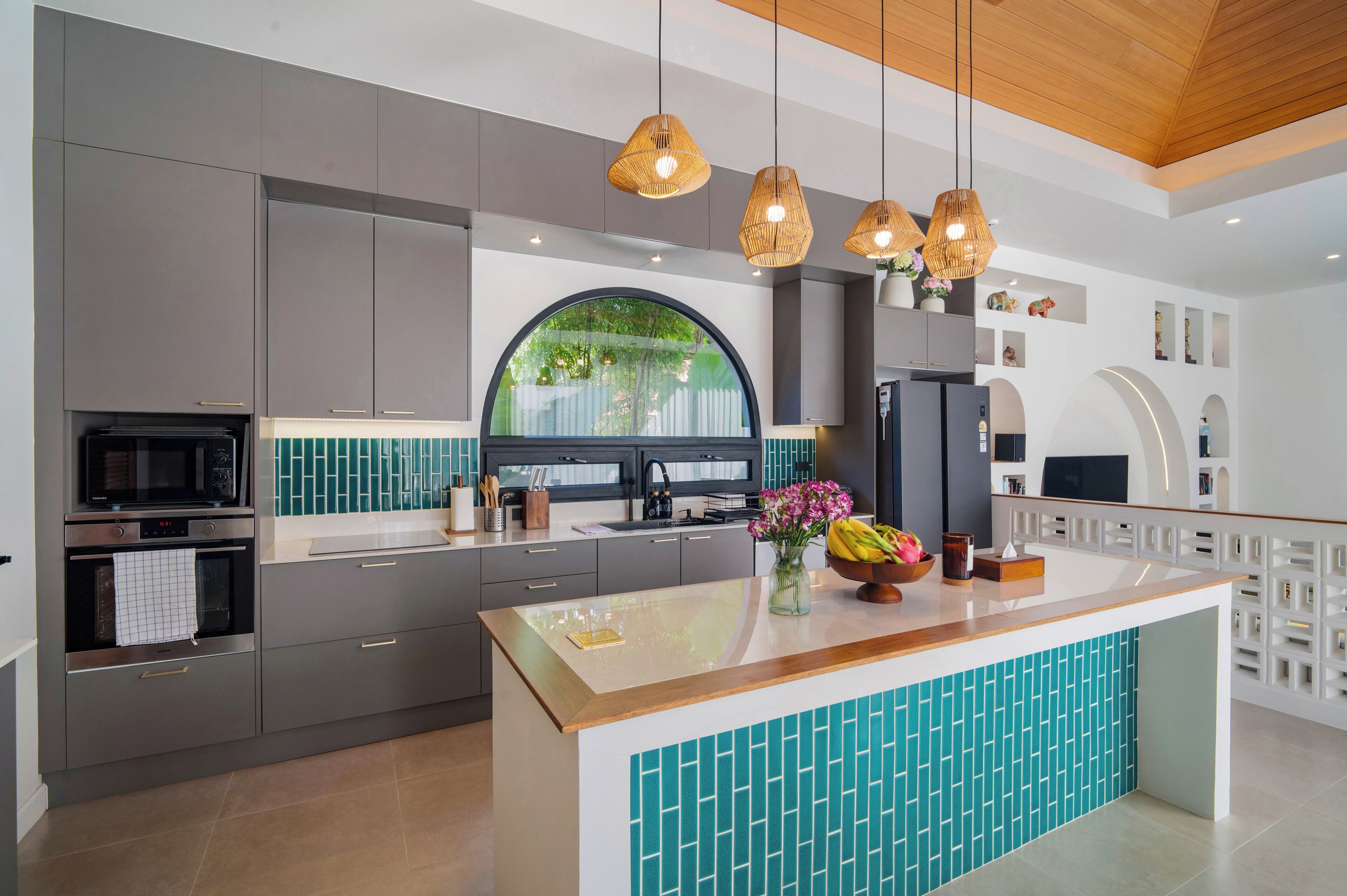 A modern kitchen with grey cabinets, a central island, and a large window.