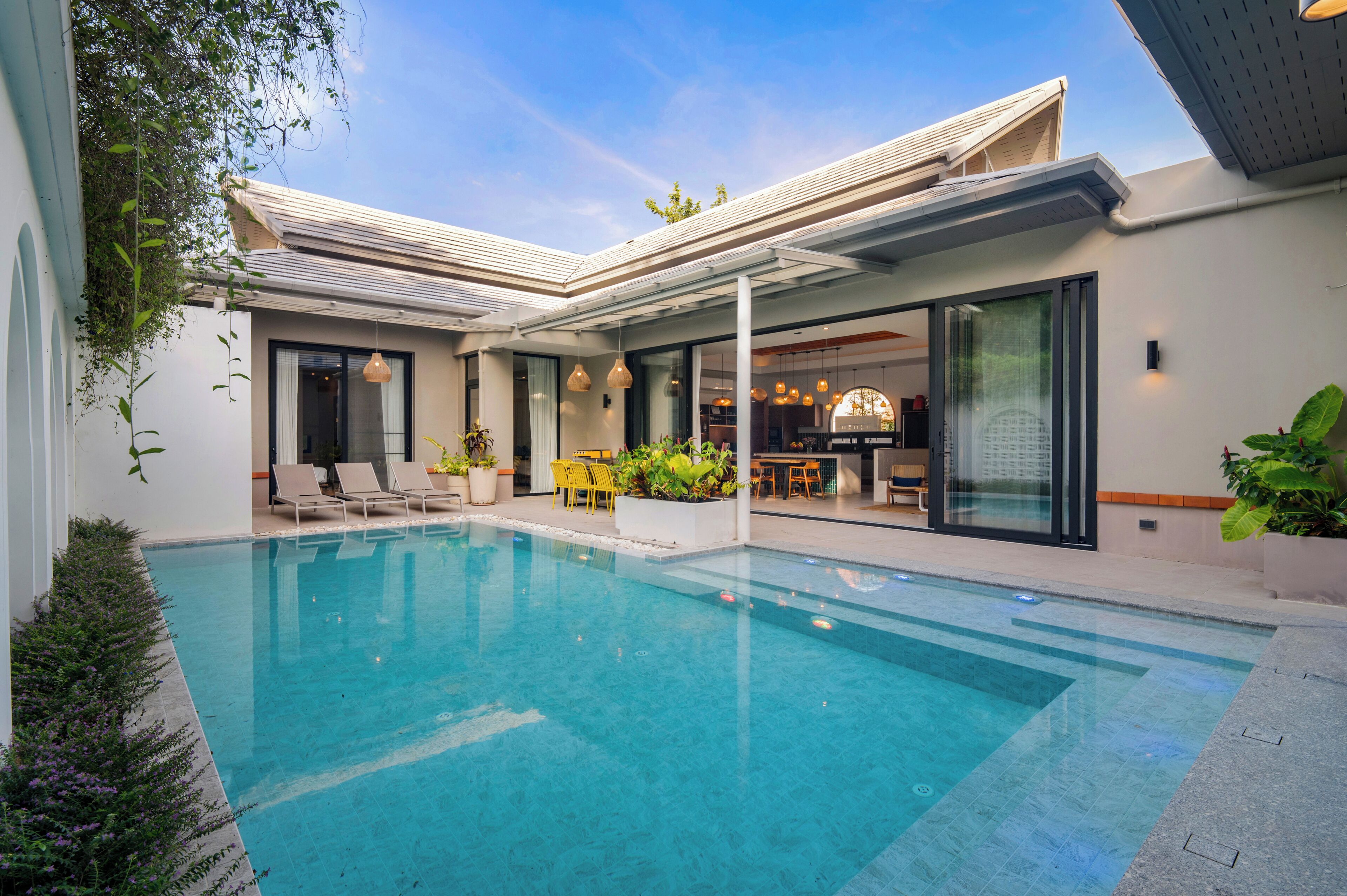 A modern house with a swimming pool, outdoor seating, and a dining area.