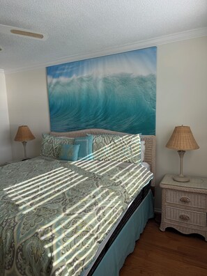 A bedroom with a large bed, two bedside tables, and a wall mural of a wave. -  2-bedroom Gulf front condo private sandy white beach, unforgettable sunsets. (Indian Shores)