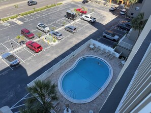 Une piscine sur le toit offrant une vue sur un parking et un immeuble.