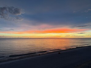 Una spiaggia al tramonto, con acque calme e cielo sereno.