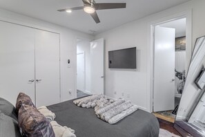 Een slaapkamer met een bed, een plafondventilator, een tv aan de muur en een kledingkast.