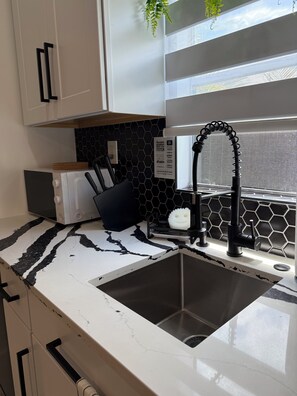 Eine Küche mit einem schwarzen Wasserhahn, einer Spüle, einem Toaster und einer Spritzschutzeinrichtung mit Wabenmuster.